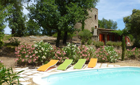 The swimming pool viewed from the garden. There are 4 sun loungers and the Moulin is in the background.